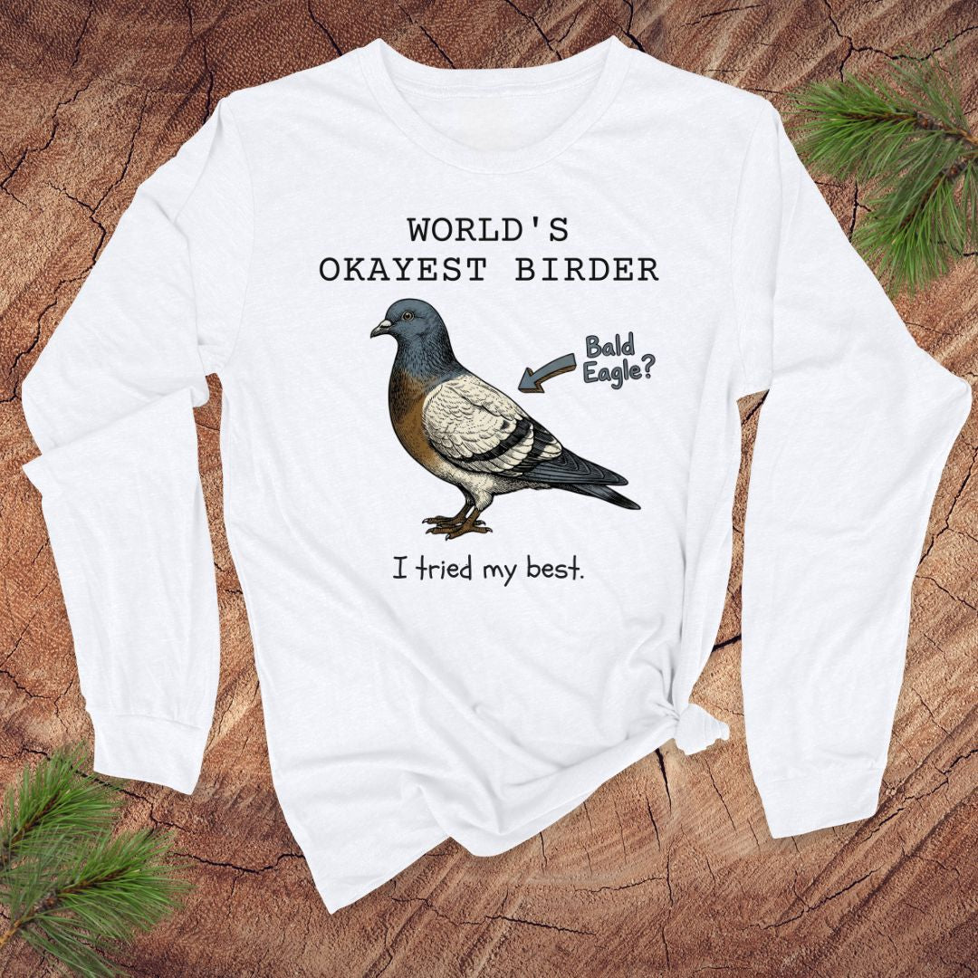 White long-sleeve shirt with a pigeon graphic and text, 'world's okayest birder' on a wooden surface