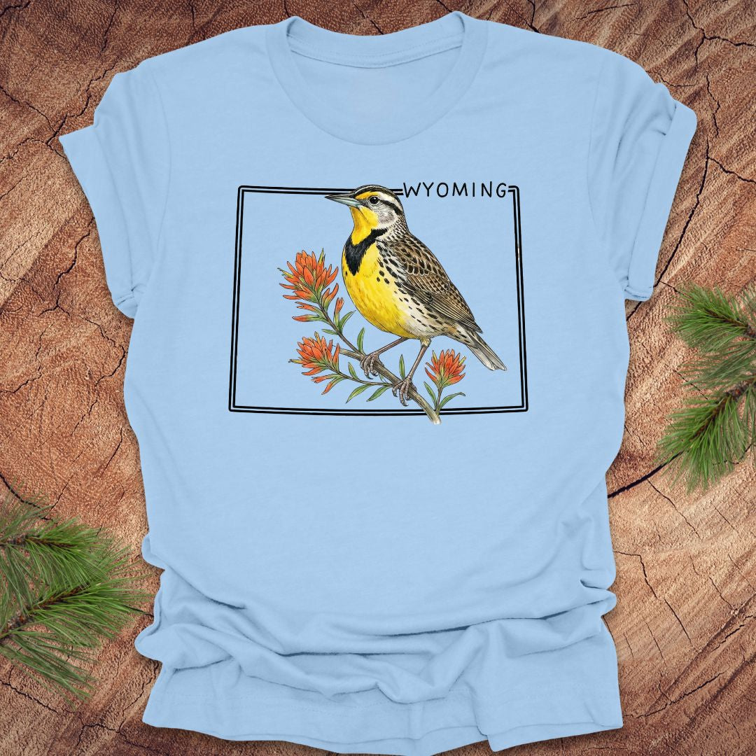Light blue t-shirt with a bird graphic and 'Wyoming' text on a wooden surface