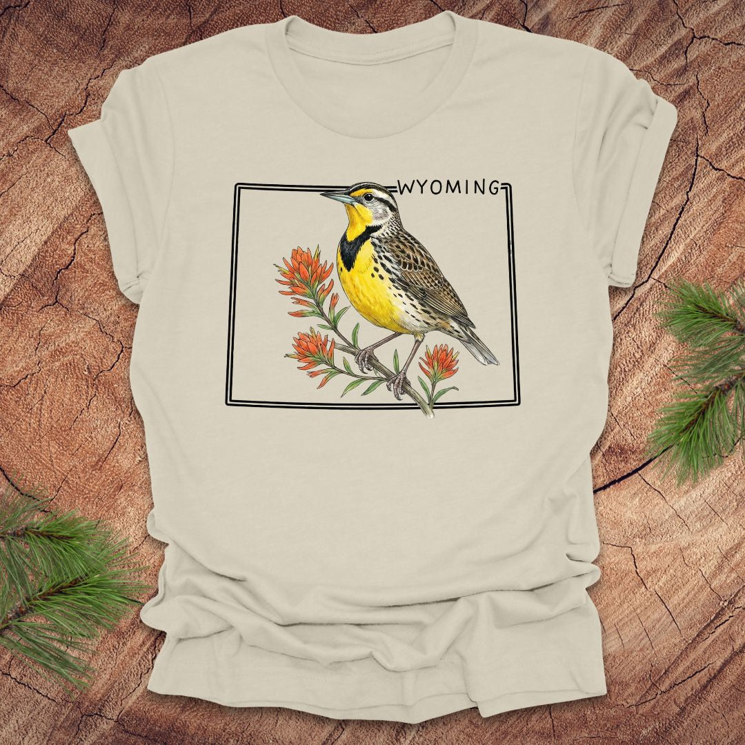 Beige t-shirt with a bird graphic and 'Wyoming' text on a wooden surface