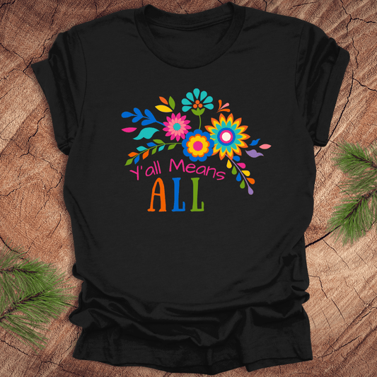 Black t-shirt with colorful floral design and text 'Y'all Means All' on a wooden surface