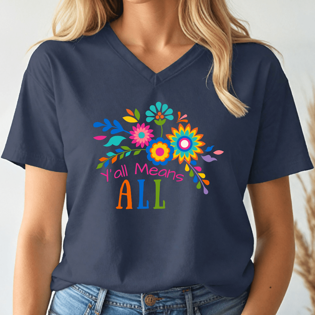 Person wearing a navy blue v-neck t-shirt with colorful floral design and text, 'Y'all Means All'.