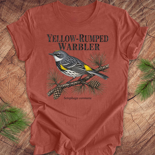 Rust colored t-shirt with yellow-rumped warbler graphic and text on a wooden surface.