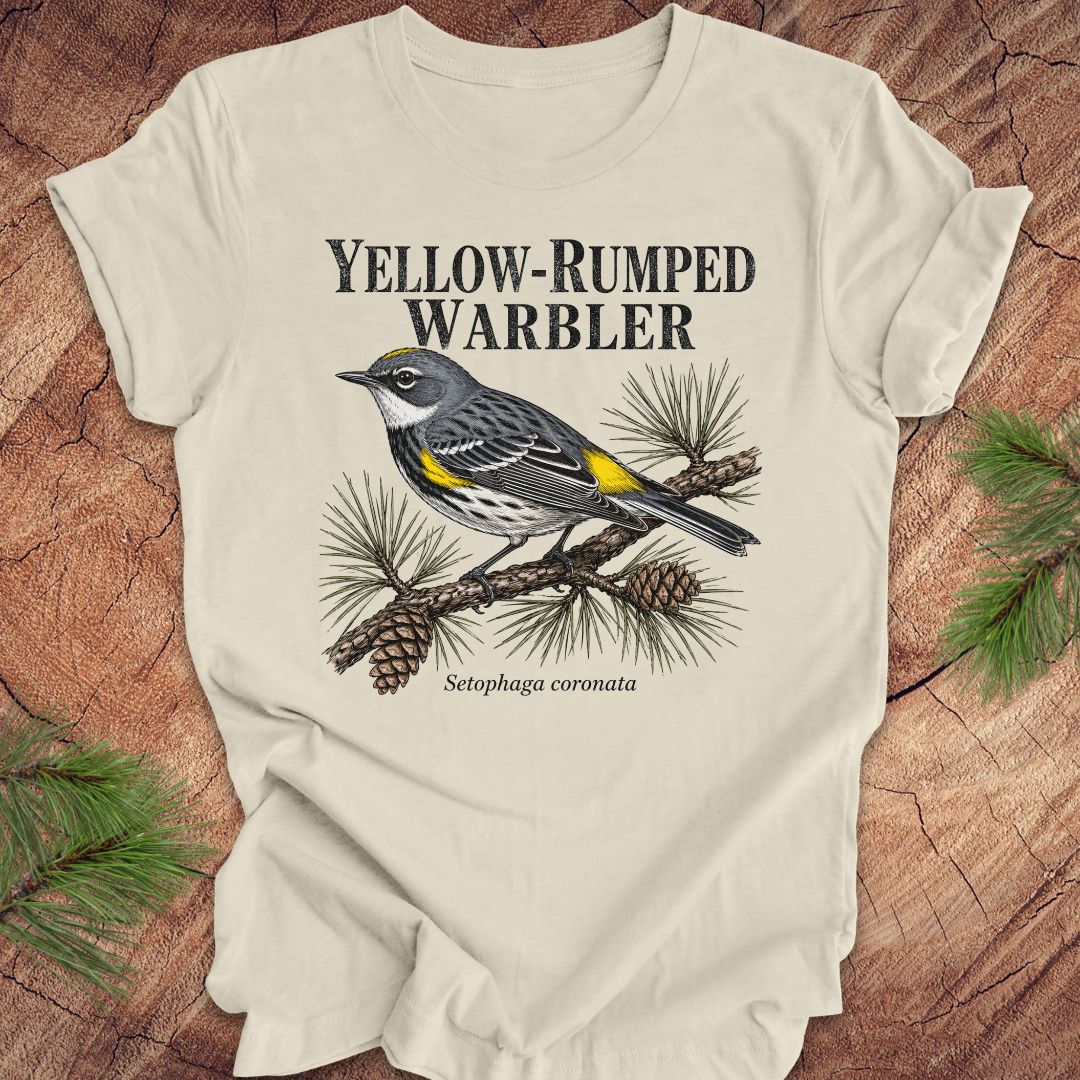 Beige t-shirt with yellow-rumped warbler graphic and text on a wooden surface.