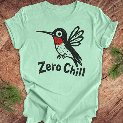 Mint green t-shirt with a black and red hummingbird graphic and 'Zero Chill' text on a wooden surface.