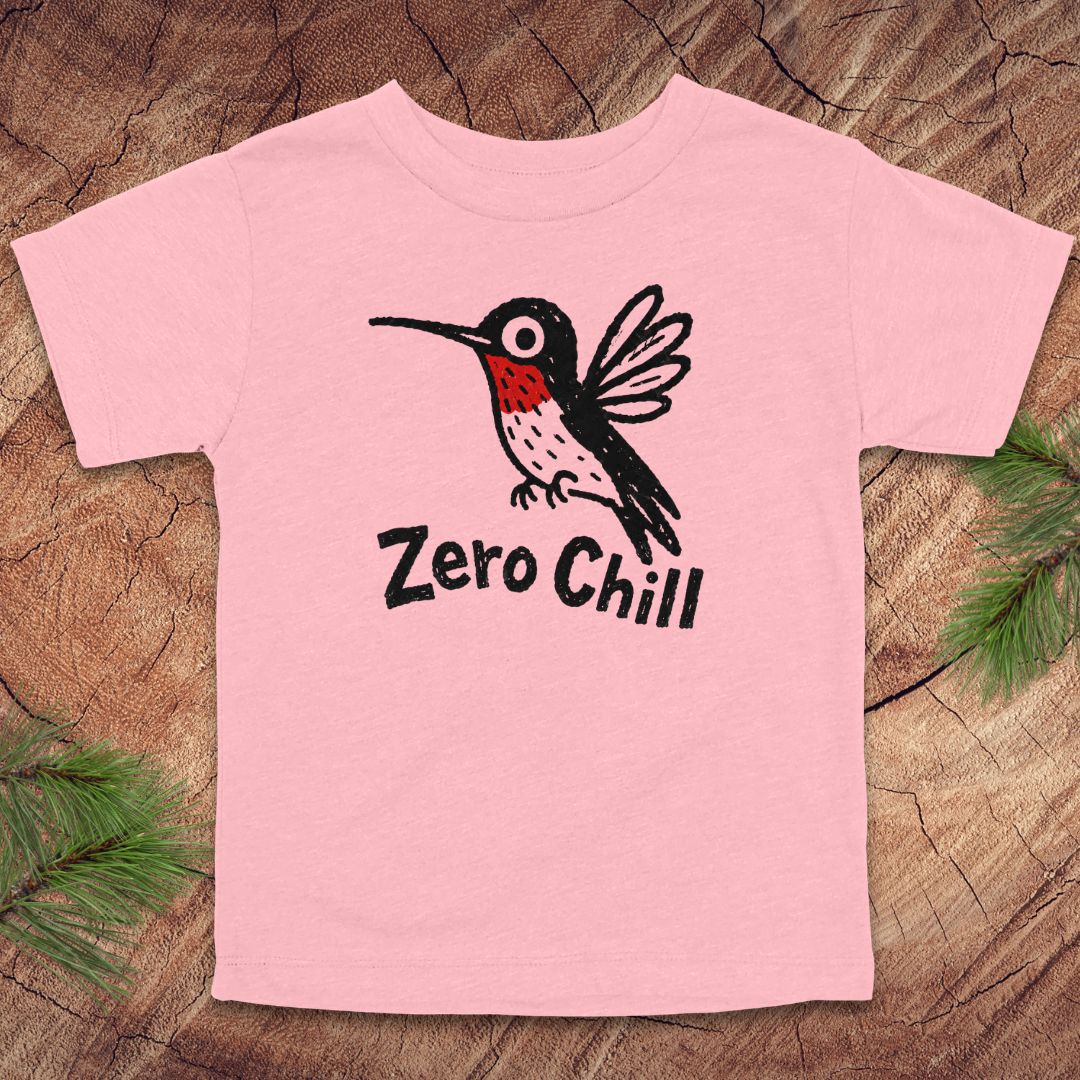 Pink t-shirt with a hummingbird graphic and 'Zero Chill' text on a wooden surface.