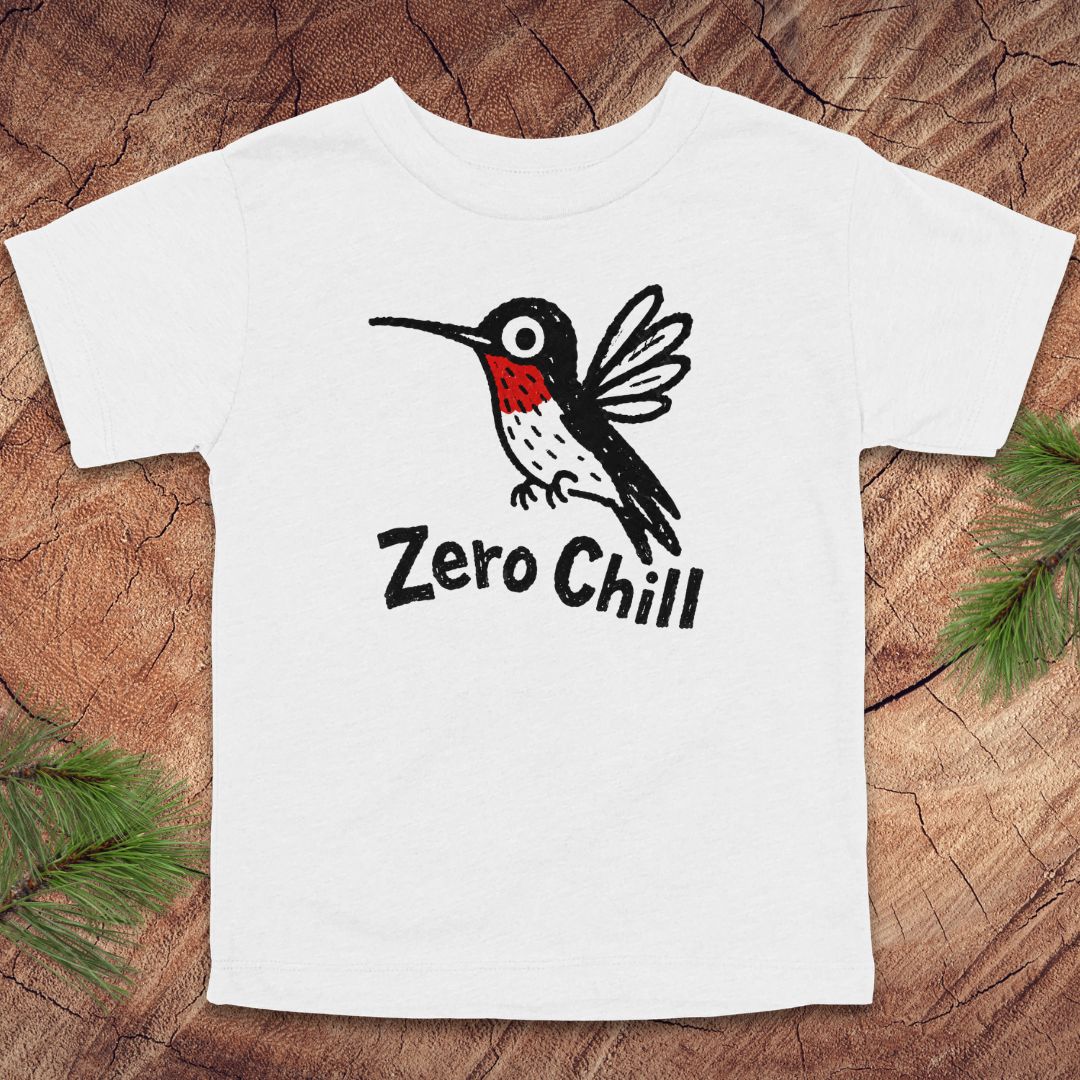 White t-shirt with a black and red bird graphic and 'Zero Chill' text on a wooden surface.